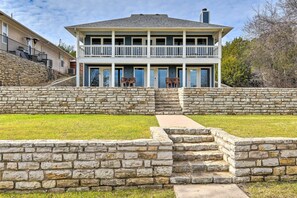 A two-story house with a stone retaining wall and a balcony. - Lake Dayz Granbury Retreat w/ Private Dock! (Granbury)