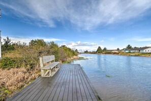 Eine Holzterrasse erstreckt sich über einen ruhigen Fluss, mit einer Bank und dichter Vegetation an einer Seite.