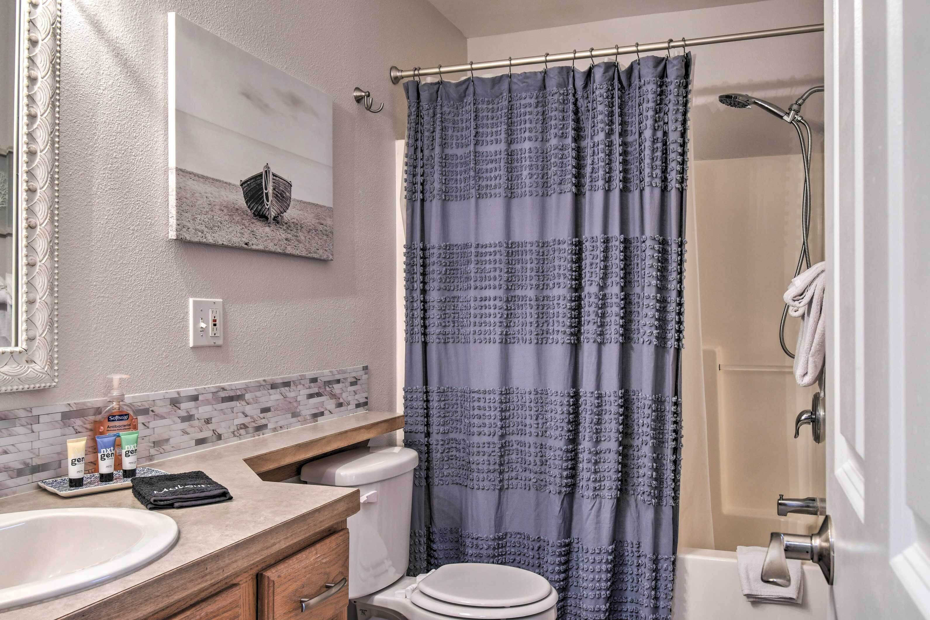 Un baño con cortina de ducha, lavabo, inodoro y espejo.