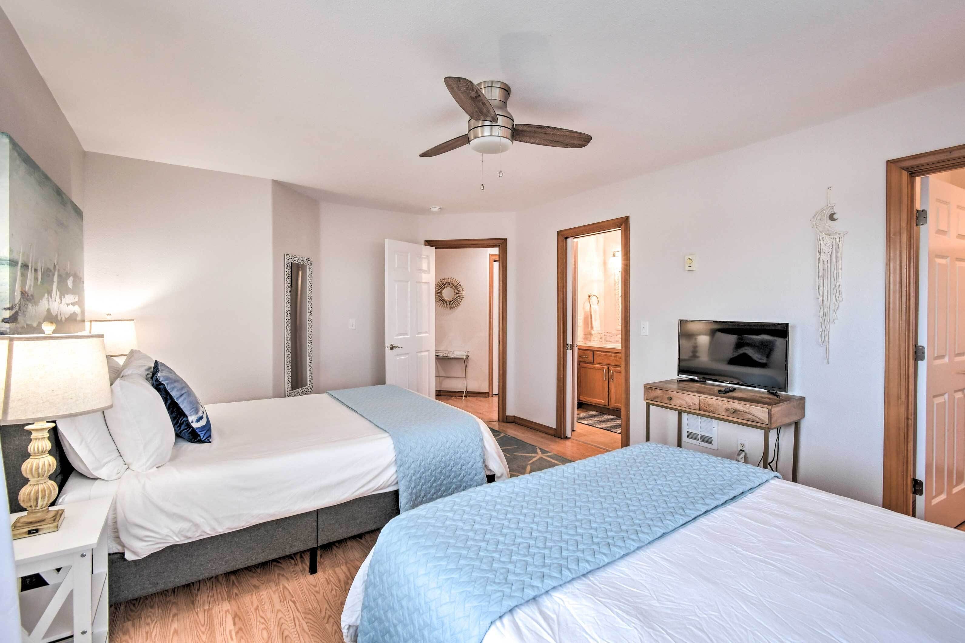 Ett hotellrum med två sängar, en takfläkt, en TV och ett litet skrivbord.