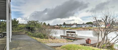 Een terras aan het meer met een betonnen pad, een houten terras en een bankje.