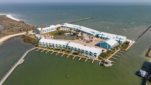 Vista aérea de un hotel costero con varias edificaciones, un muelle y un puerto deportivo.