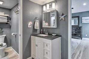 A bathroom with a white vanity, a large mirror, and a starfish decoration on the wall.