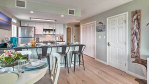 Una cocina moderna con armarios blancos, un refrigerador de acero inoxidable y una isla central con taburetes de bar.