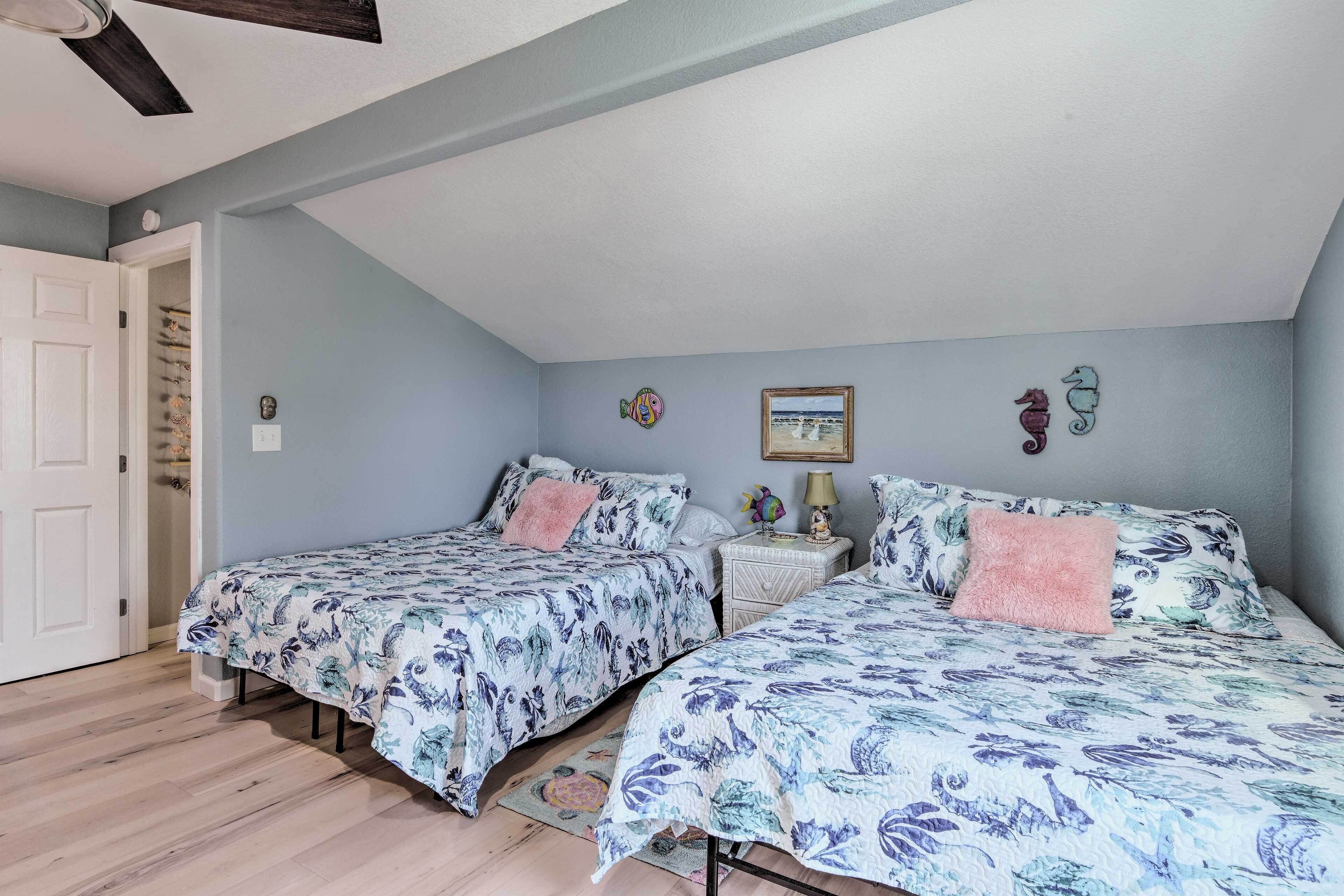 Ein Schlafzimmer mit zwei Betten, einem Deckenventilator, einer Tür und einem kleinen Tisch mit Dekoration.