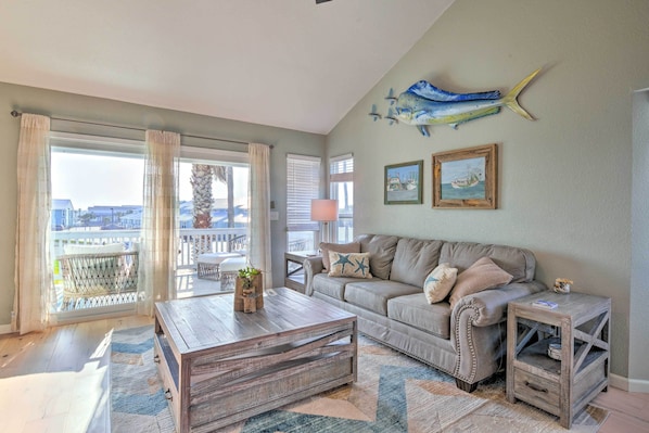 A living room with a large window, a wooden coffee table, a beige sofa, and a small side table.