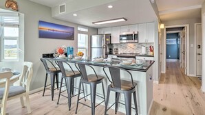Una cocina moderna con una isla central, taburetes de bar y vistas al exterior.