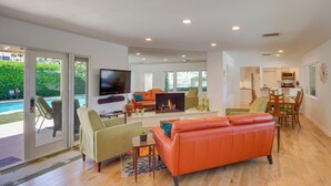 A spacious living area with a fireplace, a television, and a dining area with chairs and a table. - Patio, Pool & Mountain Views: Palm Springs Home! (Palm Springs)