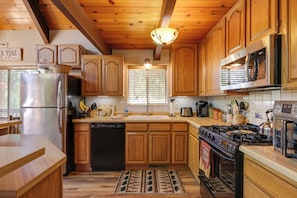 A kitchen with wooden cabinets, a stainless steel refrigerator, a stove, and a microwave. - Furnished Deck: High Sierra Cabin in Twain Harte! (Mi-Wuk Village)