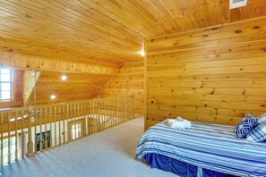 Ein Holzhüttenraum mit einem Bett, einem Fenster und einer Treppe.