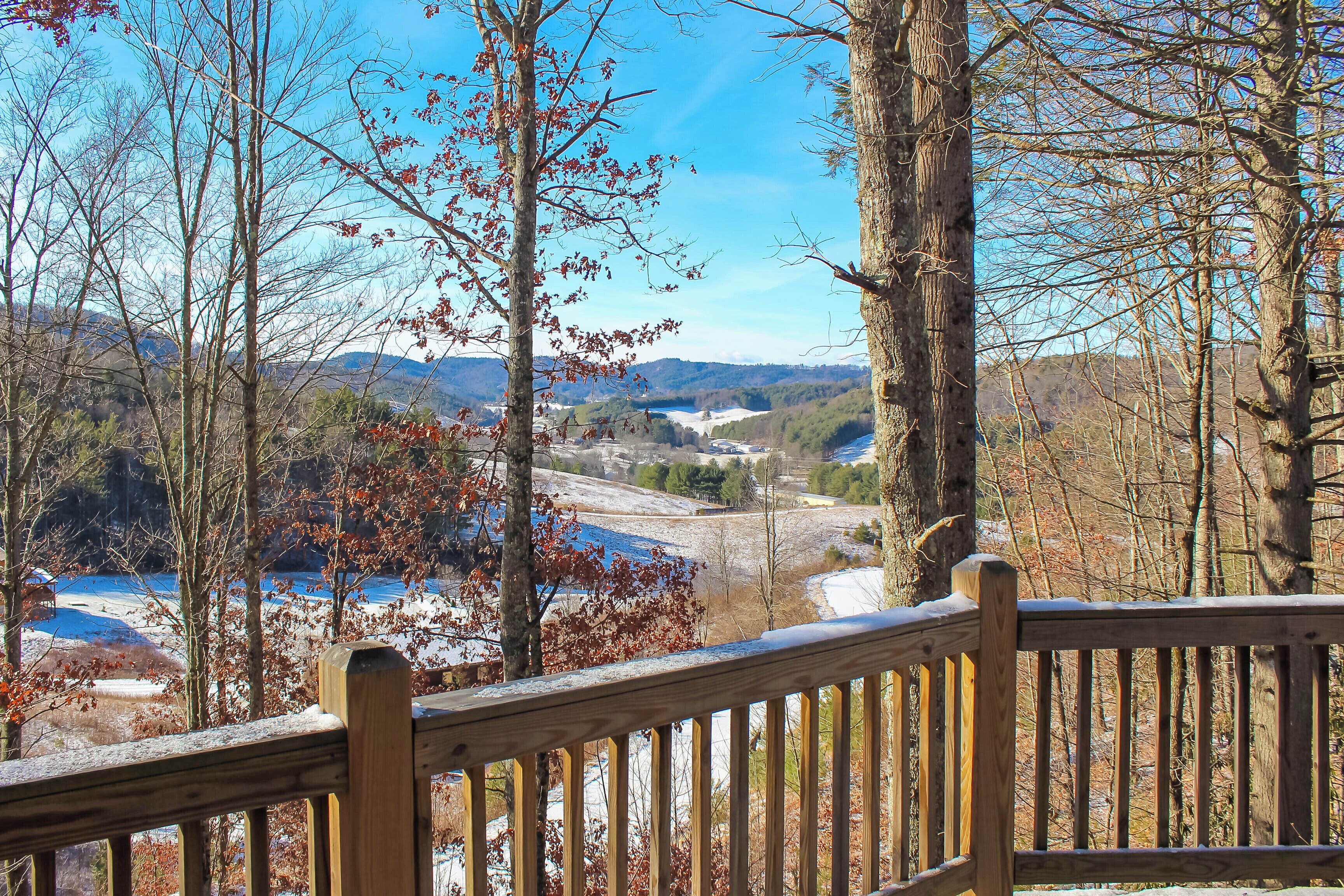 A wooden deck overlooking a valley with trees and a distant view of mountains.