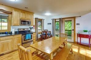 A kitchen with wooden cabinets, a microwave, an oven, and a dining table with benches. - 'A Bit of Heaven' Cabin < 13 Miles From Boone! (Fleetwood)