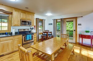 Una cocina con armarios de madera, un microondas, un horno y una mesa de comedor con bancos.