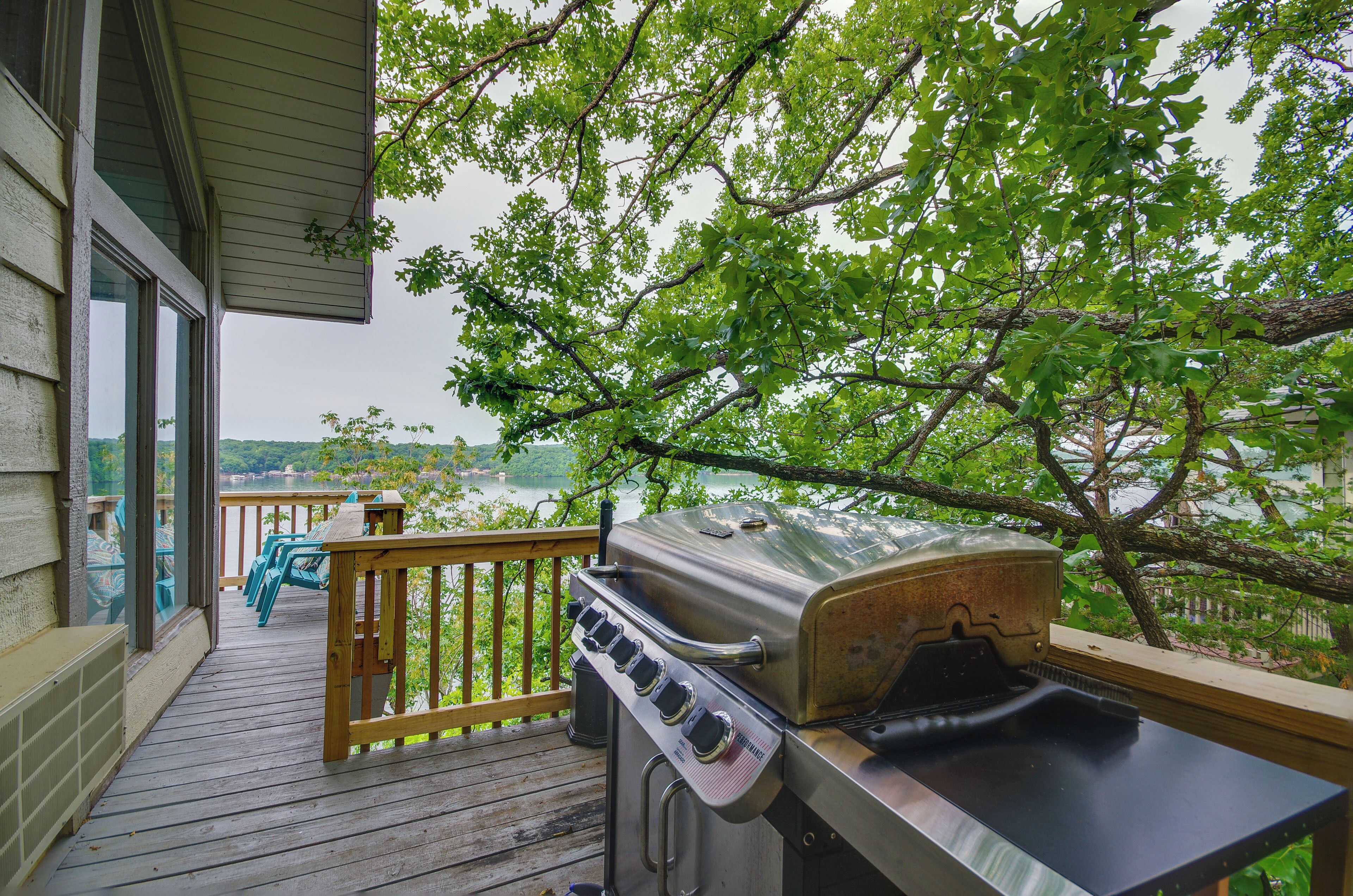 Une terrasse avec un barbecue et des chaises donnant sur un lac.