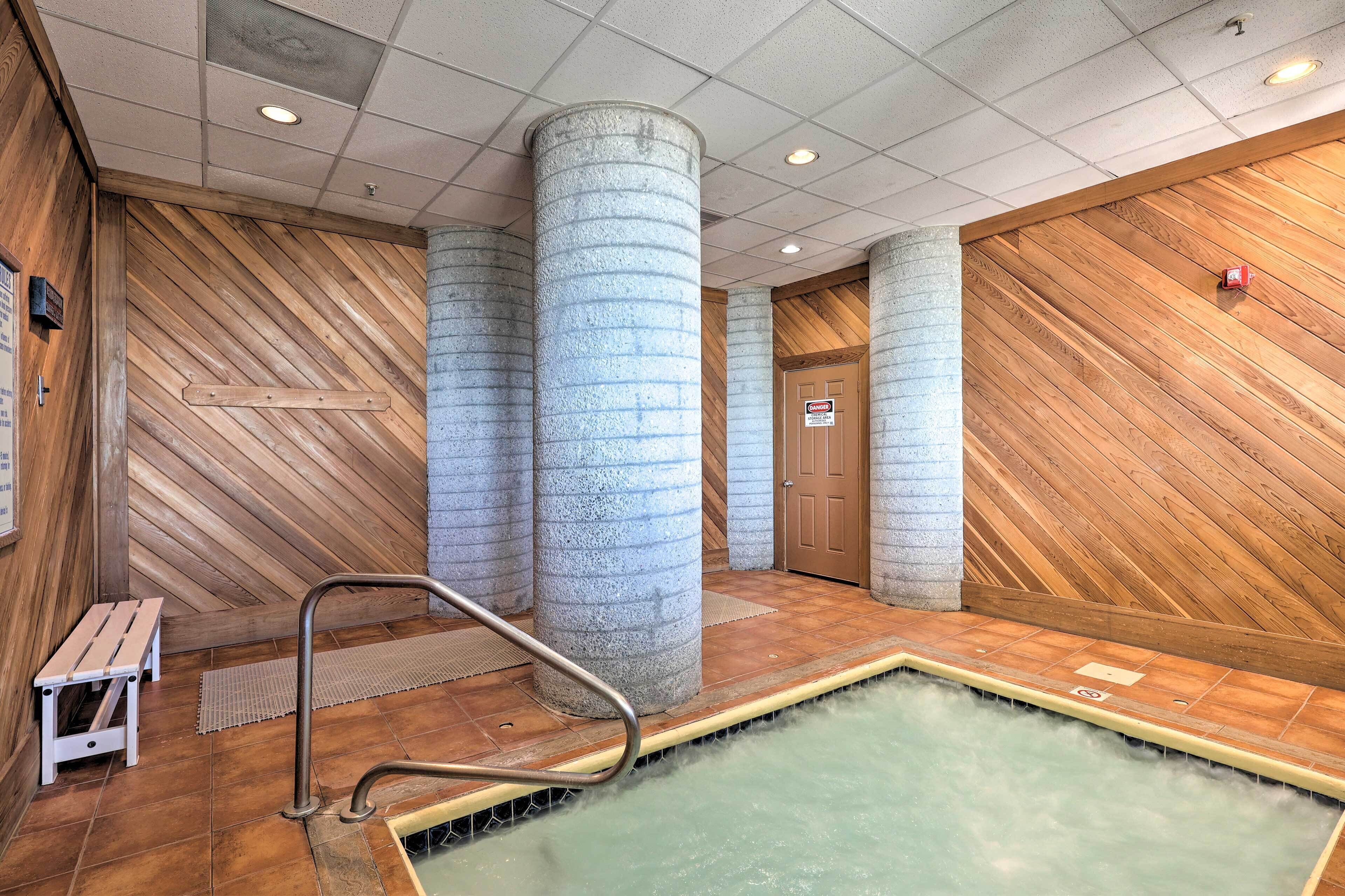 Un espacio de spa con hidromasaje, paredes de madera y pilares de piedra.