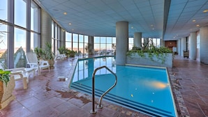 An indoor swimming pool with clear views of the city skyline, surrounded by white lounge chairs and potted plants. - Near Sugar Mountain: Renovated Condo w/ Views! (Banner Elk)