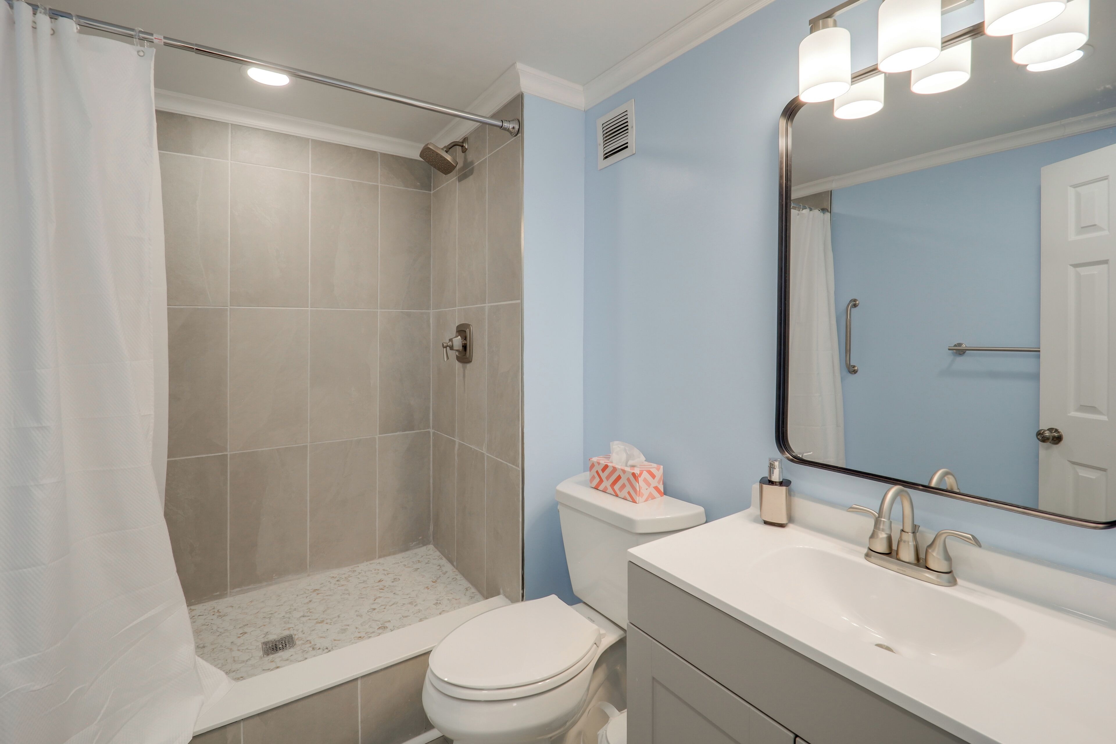 Une salle de bain équipée d’une douche, de toilettes, d’un lavabo et d’un miroir.