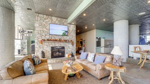 A spacious living area with a stone fireplace, leather sofas, and a coffee bar sign. - Near Sugar Mountain: Renovated Condo w/ Views! (Banner Elk)