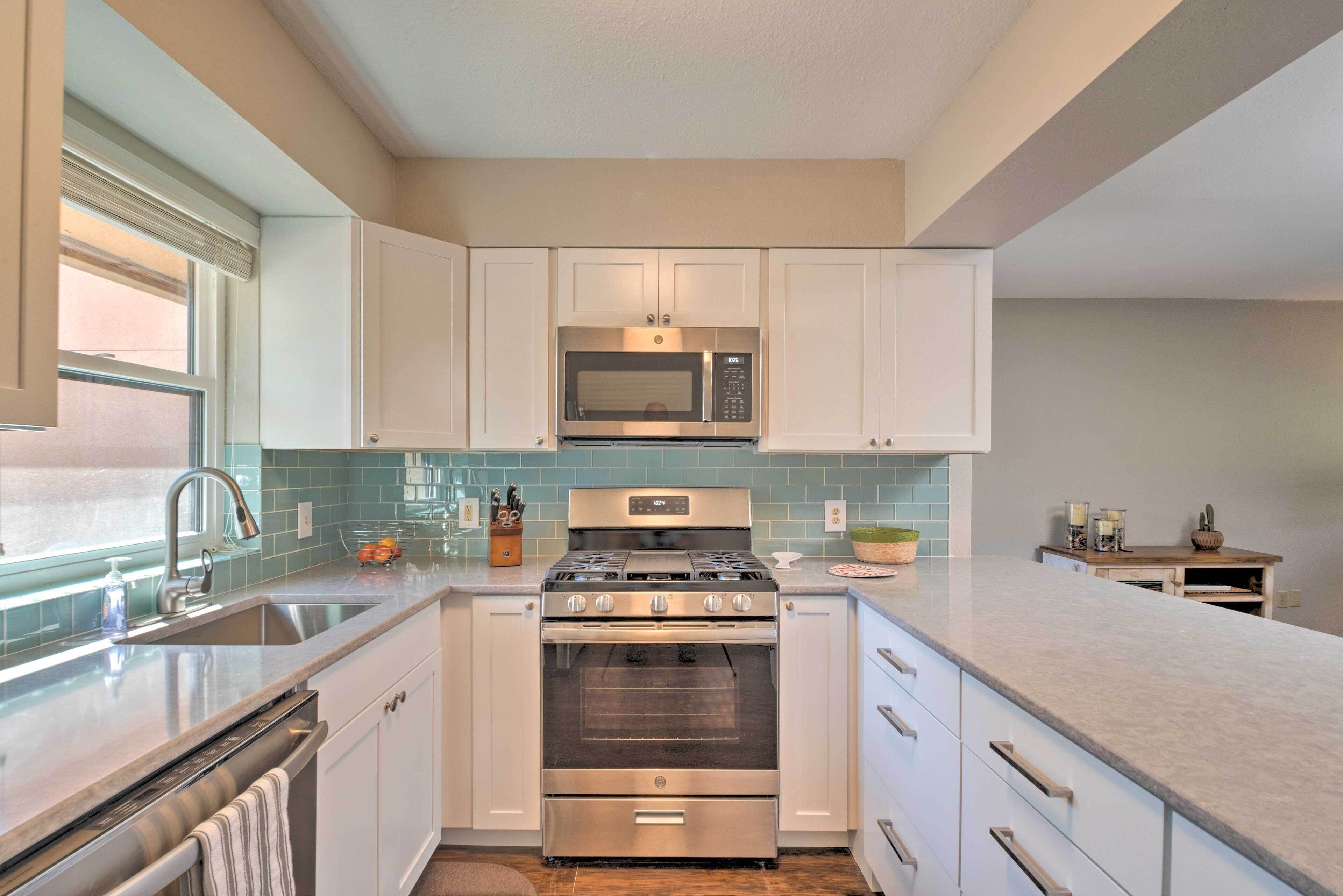 A kitchen with white cabinets, a stainless steel stove, a microwave, and a sink.