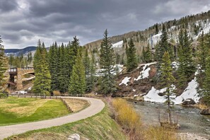 A winding path beside a river, surrounded by evergreen trees and a snow-capped mountain in the background. - Spacious Vail Condo: Steps From Eagle Bahn Gondola (Vail)