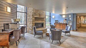 A spacious living area with a stone fireplace, modern furniture, and a large window providing a view of the outdoors. - Spacious Vail Condo: Steps From Eagle Bahn Gondola (Vail)