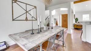 A spacious dining area with a rustic wooden table, metal chairs, and a decorative wall piece. - Shaded Getaway w/ BBQ & Fire Pit in Austin! (Austin)