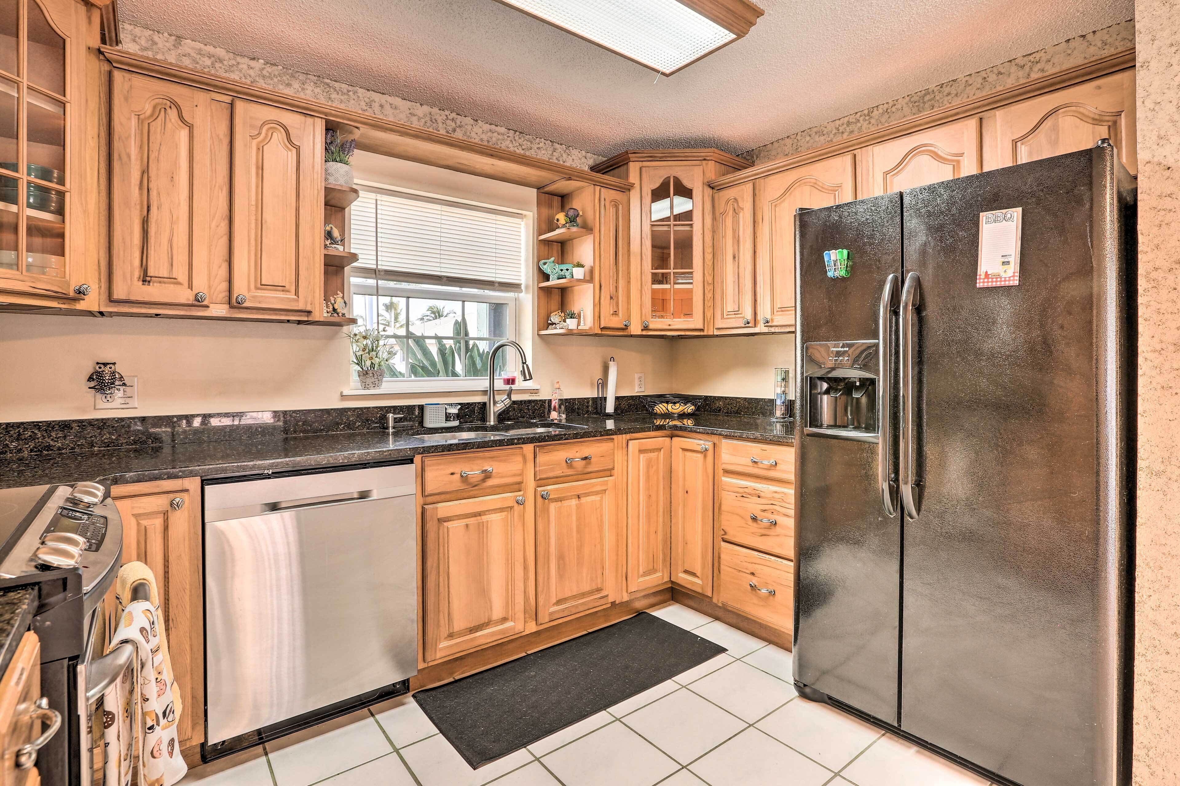 A kitchen with wooden cabinets, a stainless steel refrigerator, and a window with blinds.