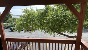 A wooden deck with a view of a parking lot and a tree.