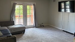 A living room with a sofa, a TV, and a sliding glass door.