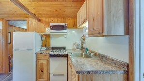 A compact kitchen with wooden cabinets, a white refrigerator, a stove, and a microwave. - Rustic Cabin w/ Fire Pit, Steps to Sand Lake! (Stone Lake)