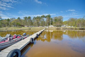 A wooden dock extending into a calm body of water with a boat moored at the end.