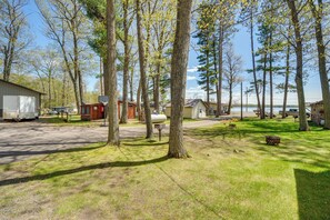A campground with RVs, a small cabin, and a lake in the background.