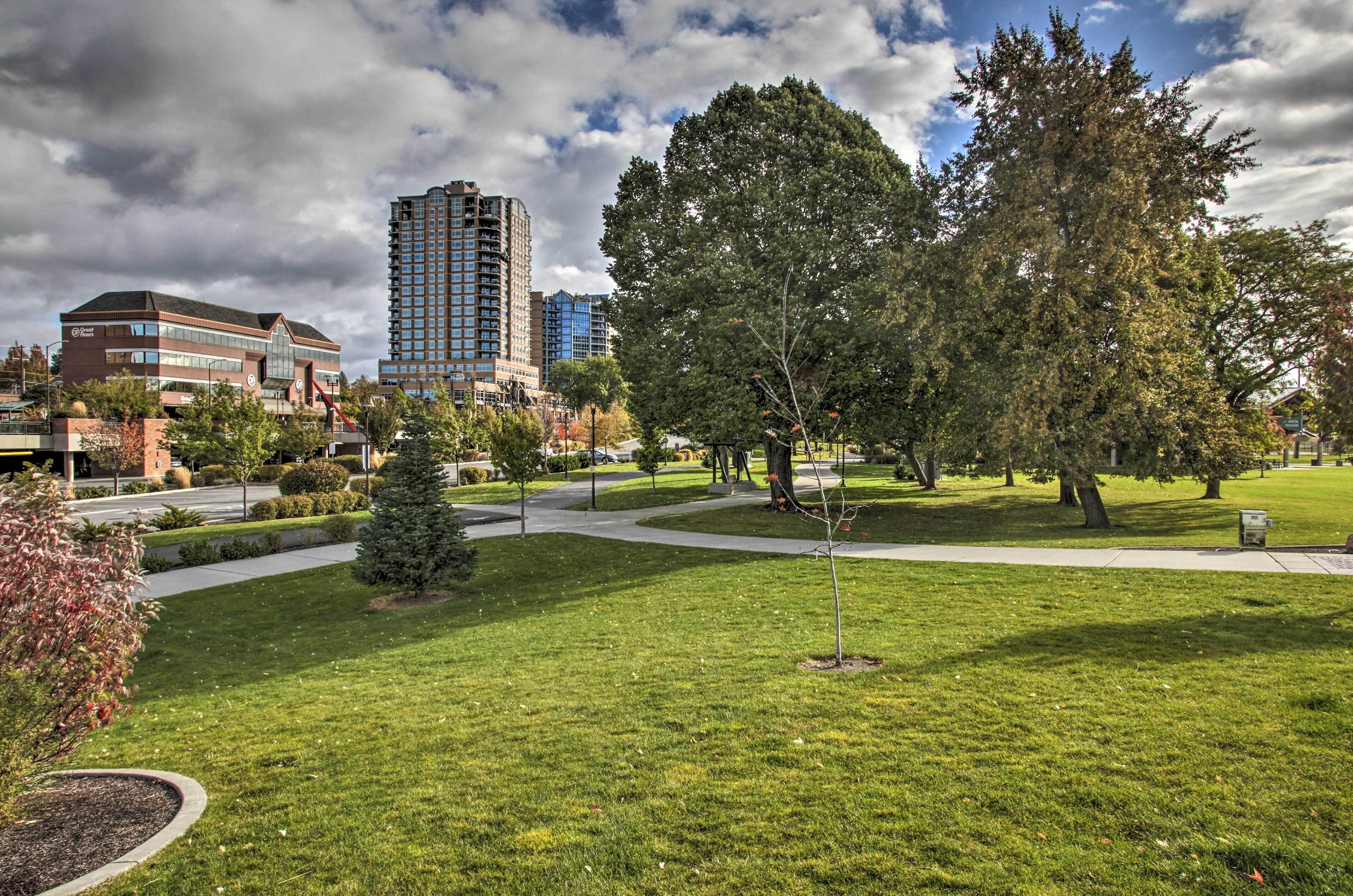 A park with green grass, trees, and a building with a sign.