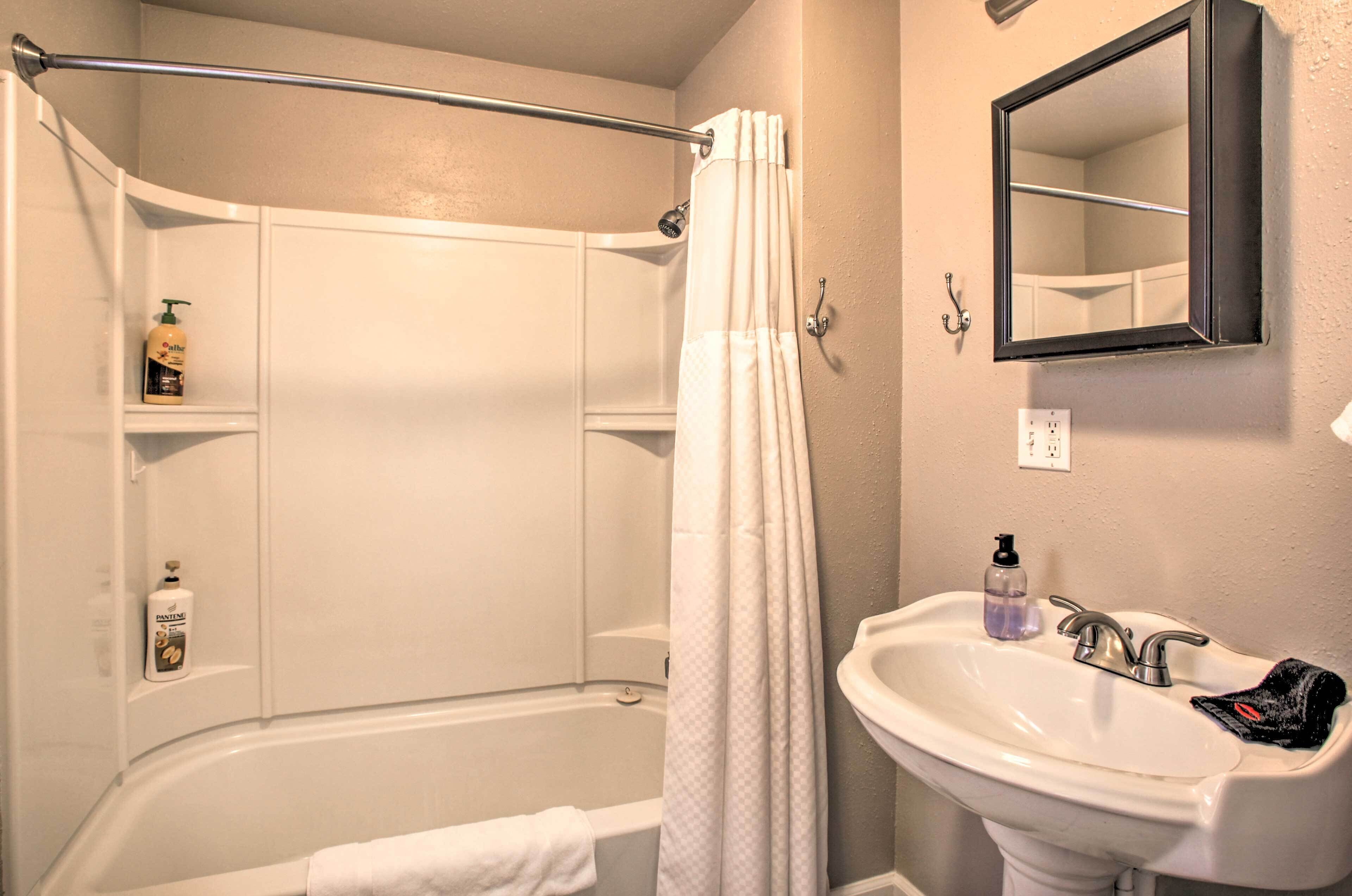 A bathroom with a bathtub, a sink, a mirror, and a shower curtain.