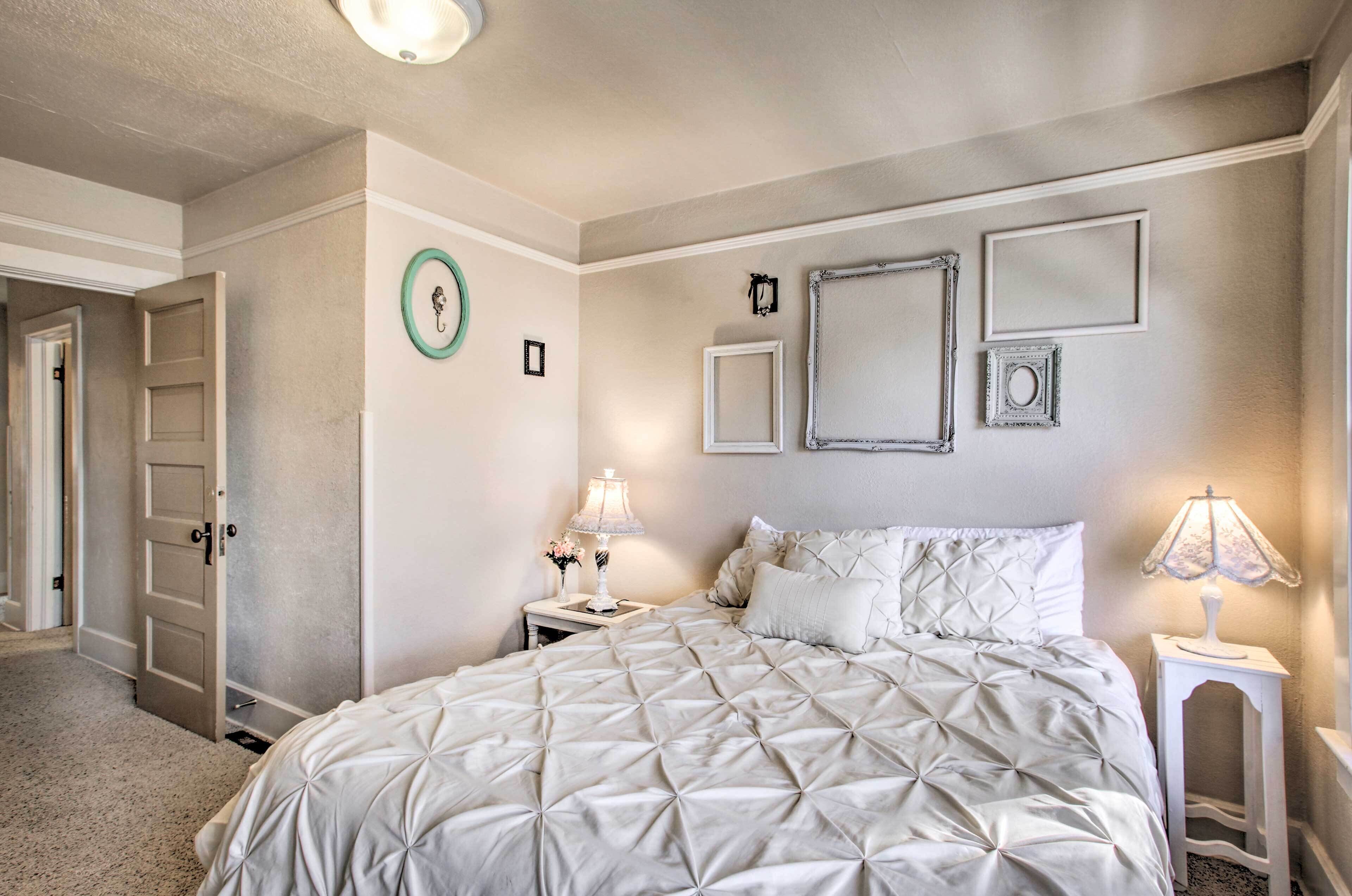 A bedroom with a large bed, two bedside tables, and a door leading to another room.