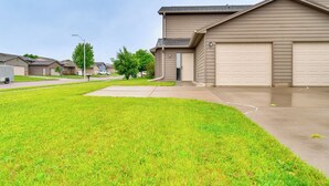 A residential neighborhood with houses, a well-maintained lawn, and a driveway leading to a garage. - Cozy Sioux Falls House - Walk to Park! (Sioux Falls)