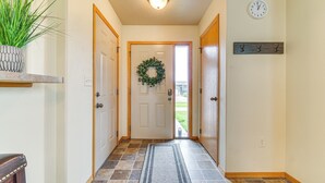 A hallway with a door, a wreath, a clock, and a plant on a shelf. - Cozy Sioux Falls House - Walk to Park! (Sioux Falls)