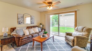 A living room with a leather couch, a wooden coffee table, a recliner, and a ceiling fan. - Cozy Sioux Falls House - Walk to Park! (Sioux Falls)