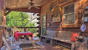 Eine rustikale Holzhütte mit Veranda, einem Tisch mit roter Tischdecke und einer Bank mit rotem Kissen.