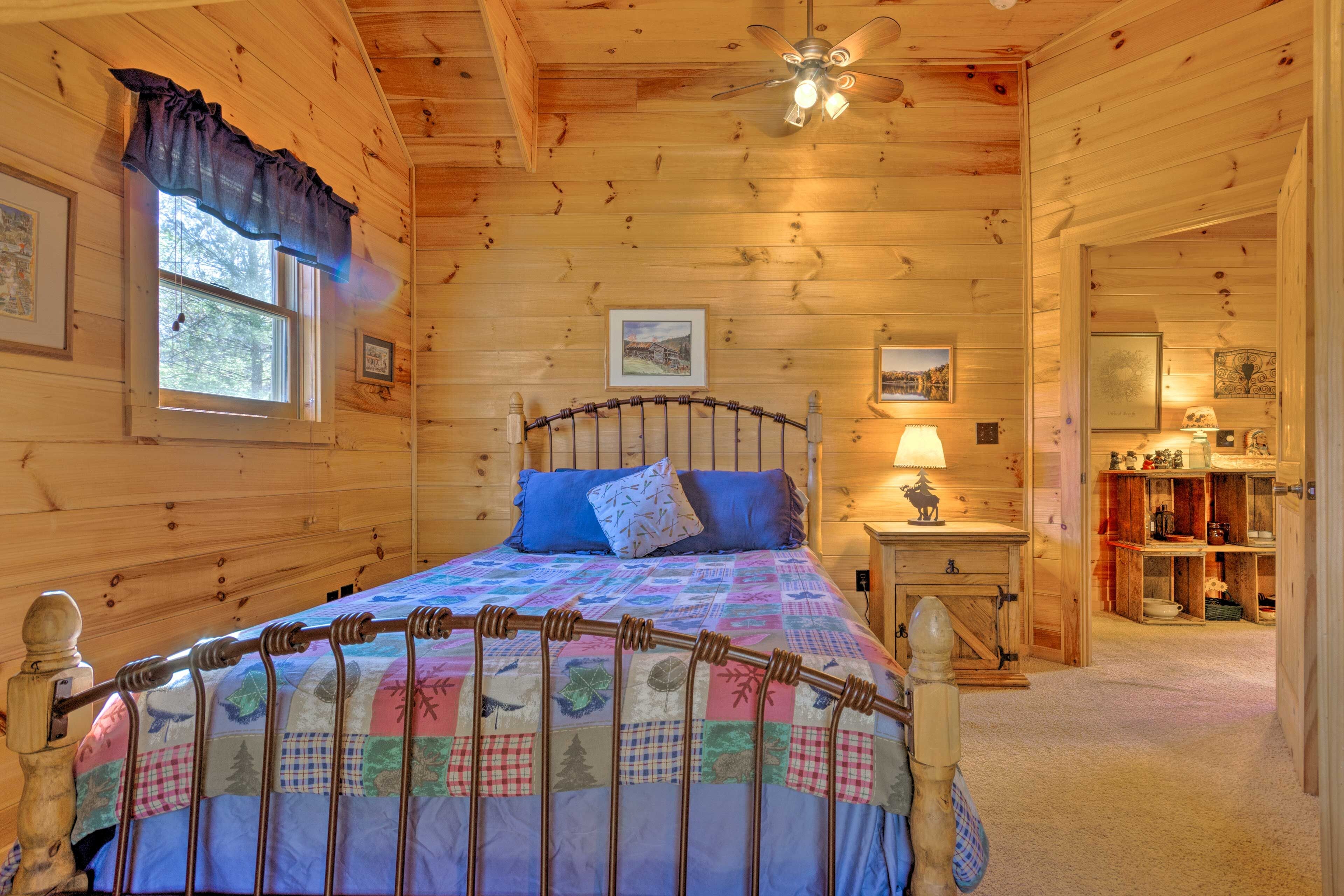 A wooden cabin bedroom with a bed, a nightstand, a lamp, and a bookshelf.
