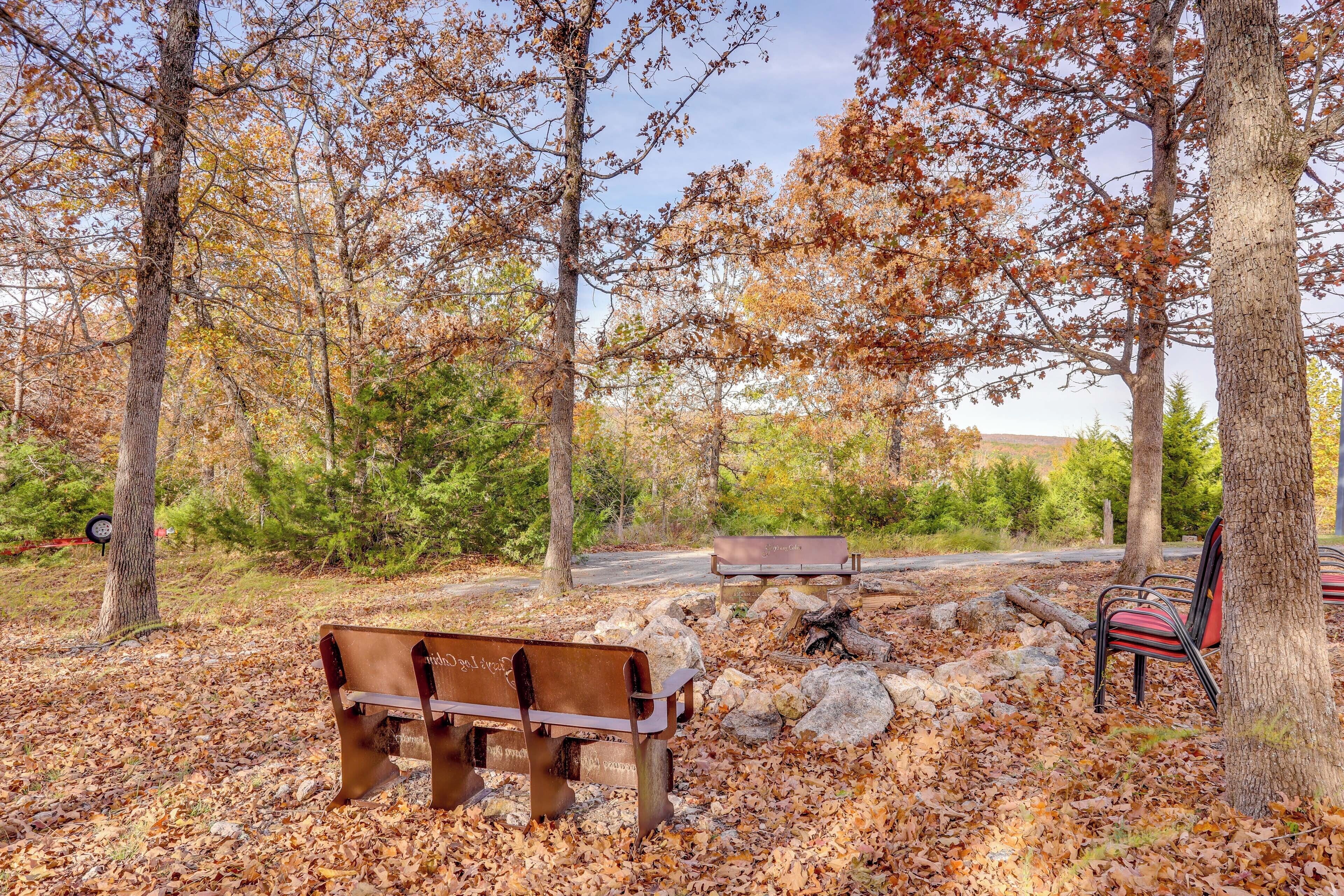 A park with benches and a picnic table surrounded by trees and rocks.