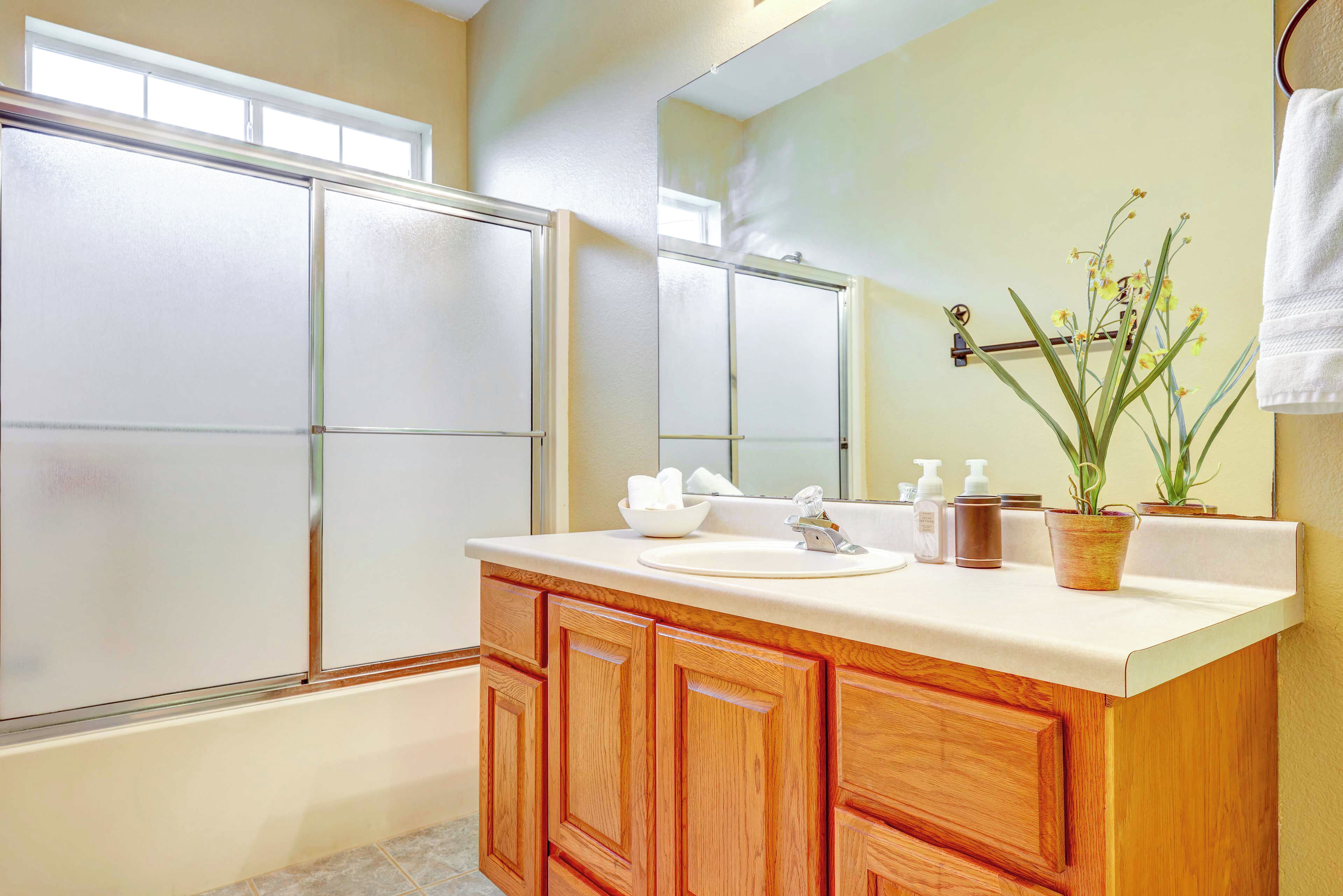 A bathroom with wooden cabinets, a sink, and a mirror.