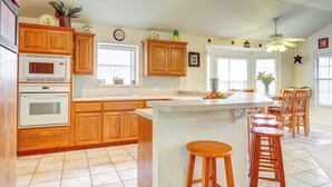 A kitchen with wooden cabinets, a microwave, and a large island with stools. - Canyon Lake Getaway w/ Fire Pit, Boat Ramp Nearby! (Canyon Lake)