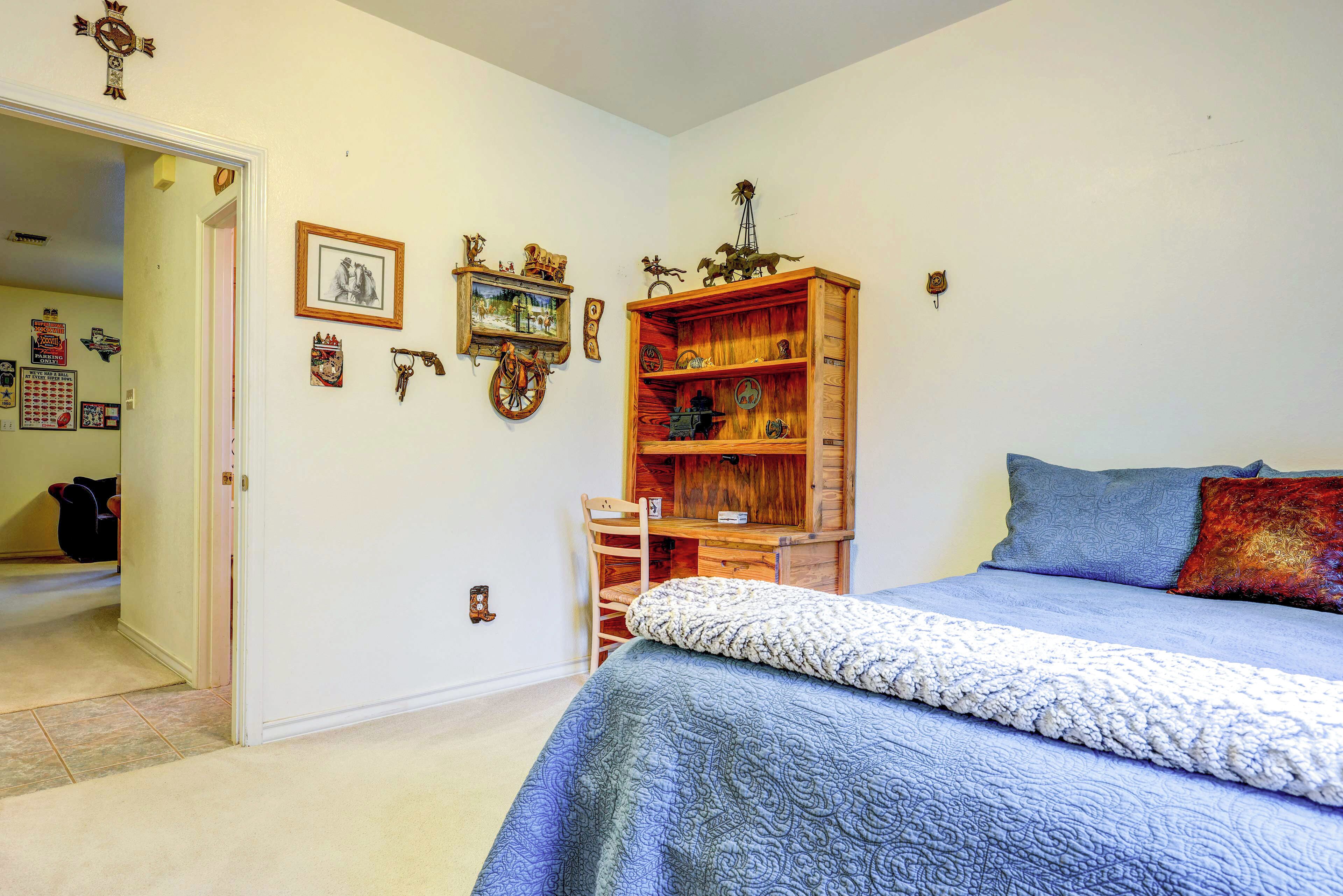 A bedroom with a bed, a wooden dresser, and wall decorations.
