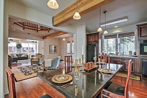 Un amplio espacio de estar con una gran mesa de comedor, vigas de madera y una cocina con armarios oscuros y un refrigerador.