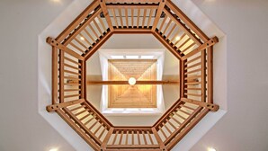 Un escalier en colimaçon en bois, doté d’un luminaire central et d’une lucarne au sommet.