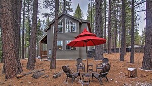 Une cabane dotée d’un patio aménagé avec du mobilier d’extérieur et un parasol rouge.