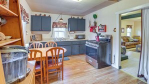 A kitchen with wooden cabinets, a dining table, chairs, a stove, and a microwave. - 'grizzly Pine' Cottage - Walk to Ski Beach Park! (Big Bear Lake)