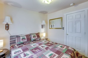 Quarto com cama, duas luminárias de cabeceira, um espelho e uma porta.