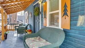 A covered porch with wicker furniture, a decorative wreath, and a blue exterior wall with tree decorations. - 'grizzly Pine' Cottage - Walk to Ski Beach Park! (Big Bear Lake)